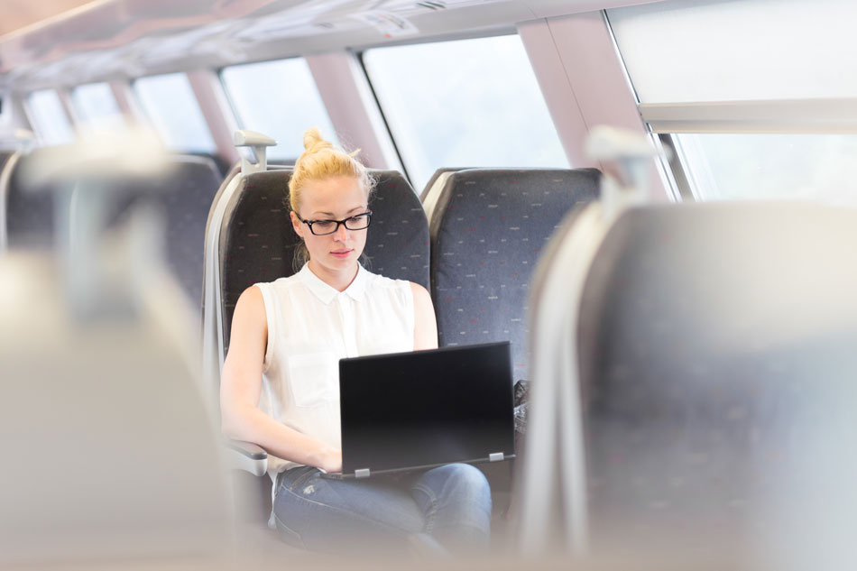 Empresária sentada e viajando de trem trabalhando no laptop. Conceito de viagens de negócios.