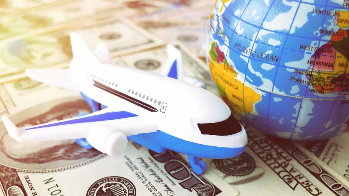 Notas de dólar com um avião e um globo terreste em miniatura sobre elas