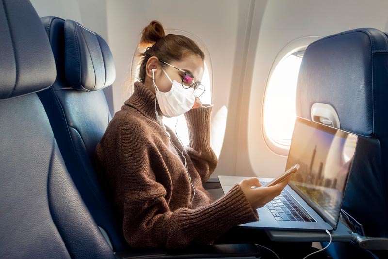 Uma jovem usando máscara facial está viajando em avião , Nova viagem normal após conceito de pandemia covid-19