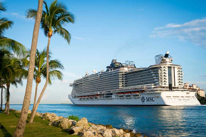 O navio de cruzeiro MSC Seaside passa por palmeiras em South Beach quando sai do porto.